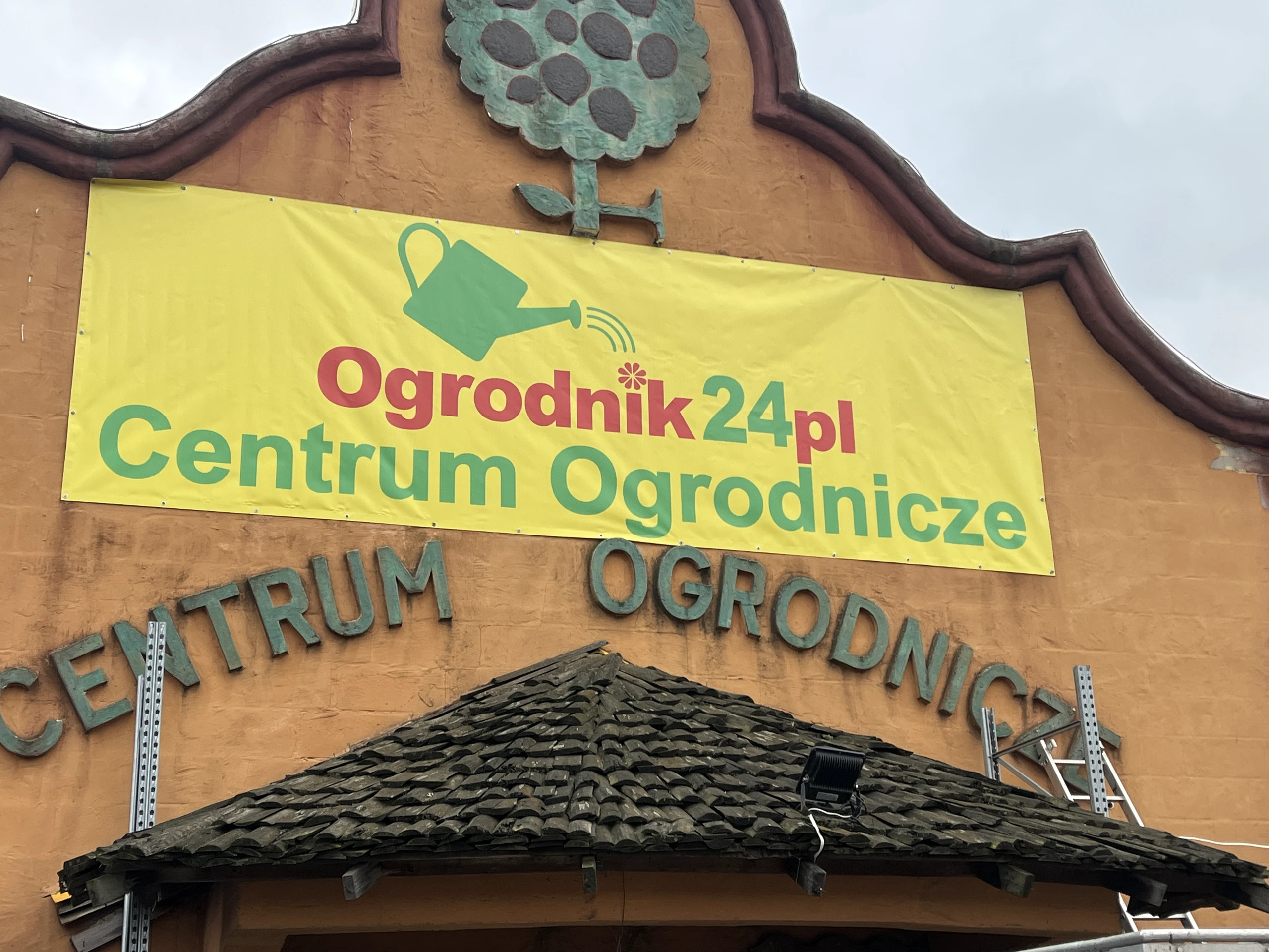 Fasada budynku centrum ogrodniczego z żółtym banerem reklamowym i metalowymi literami